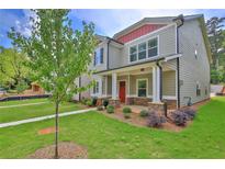 Charming two-story home featuring a red front door, a well-maintained lawn, and a covered front porch at 4571 Academy St, Acworth, GA 30101