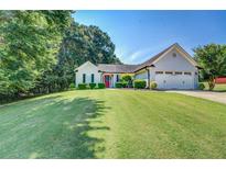 Well-maintained home with a manicured lawn, lush greenery, and a charming red front door at 2321 Sunnyview Ln, Dacula, GA 30019