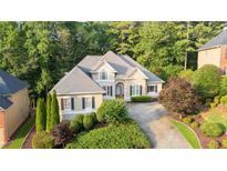 Well-manicured lawn and mature trees surround this beautiful two-story home with a neutral color scheme at 5059 Winding Hills Lane Ln, Woodstock, GA 30189