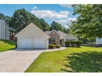 Charming single-story home with a two-car garage, lush lawn, and manicured landscaping at 2410 Napa Valley Dr, Villa Rica, GA 30180