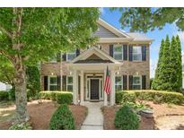 Charming brick home features manicured landscaping, covered entry, and an American flag for a welcoming curb appeal at 214 Harmony Lake Dr, Canton, GA 30115