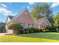 Charming brick home features well-maintained landscaping and a lush green lawn at 10050 Lauren Hall Ct, Alpharetta, GA 30022