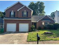 Charming two-story brick home featuring an attached two car garage and a well-maintained front yard at 5942 Idlewood Pl, Lithonia, GA 30038