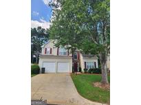 Two-story home featuring a two-car garage and red shutters accenting the beige siding at 1447 Evanston, Marietta, GA 30062