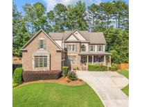 Charming brick two-story home with a manicured lawn and inviting front porch at 4771 Moon Chase Dr, Buford, GA 30519