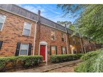 Brick townhomes boast a red front door and neatly trimmed hedges, offering charming curb appeal at 115 Winding River Dr # B, Atlanta, GA 30350