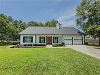 Charming single-story home featuring a red front door, well-manicured lawn, and attached two-car garage at 2335 Huntington Dr, Loganville, GA 30052