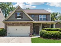 Charming two-story home featuring a stone facade, neutral siding, covered entryway, and an attached two car garage at 6202 Oakdale Ridge Se Ct, Mableton, GA 30126