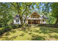 Charming two-story home with a welcoming front porch and lush green lawn surrounded by mature trees at 2121 Jep Wheeler Rd, Woodstock, GA 30188