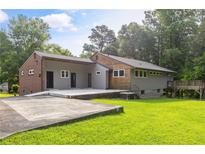 Attractive single-story home featuring gray siding, brick accents, and a large concrete patio in a lush, green yard at 4847 Lakewood Dr, Acworth, GA 30101