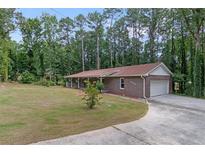 Ranch-style brick home featuring an attached garage, a well-manicured lawn, and mature trees at 6372 Valley Dale Dr, Riverdale, GA 30274