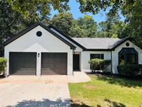 Charming one-story home with a painted brick facade, dark trim, two car garage and manicured lawn at 3021 Stone Bridge Sw Trl, Conyers, GA 30094