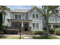 Charming two-story home with a covered front porch, manicured landscaping, and light blue wood siding at 3871 Portland Trail Dr, Suwanee, GA 30024