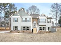 Charming two-story home featuring a stone archway, gray siding and a well-manicured lawn at 6005 Crowley Dr, Douglasville, GA 30135