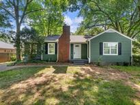 Charming green home featuring a brick chimney and well-manicured front yard surrounded by mature trees at 1560 Pontiac Se Pl, Atlanta, GA 30315