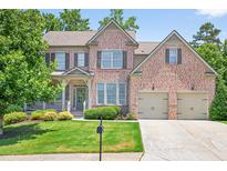 Beautiful brick home with a well-manicured lawn and attached two car garage at 5740 Zelkova Dr, Cumming, GA 30040