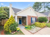 Charming home featuring a blue door and shutters, complemented by beautiful landscaping and mature trees at 1602 Buckingham Place Pl, Woodstock, GA 30188