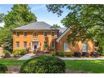 Charming, brick two-story home with mature trees, manicured shrubs, and a manicured lawn at 7575 Hunters Woods W Dr, Atlanta, GA 30350