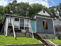 View of a historic home needing work, featuring a quaint turquoise door, small porch, and unfinished sunroom at 255 Georgia Se Ave, Atlanta, GA 30312