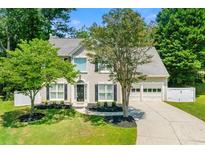 Charming two-story home with a well-manicured lawn, lush trees, a paved driveway, and an attached garage at 1095 Northpoint Trce, Roswell, GA 30076