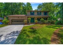 Charming two-story home with brick facade, lush lawn, and mature trees offering shade and curb appeal at 2775 Doaks Run Ct, Tucker, GA 30084