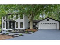 Charming two-story home with white siding, black trim, manicured landscaping, and attached two-car garage at 772 Brookwood Sw Ter, Lilburn, GA 30047
