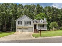 Charming two-story home with gray siding, black shutters, and a two-car garage, nestled on a large wooded lot at 1049 Braddock Cir, Woodstock, GA 30189