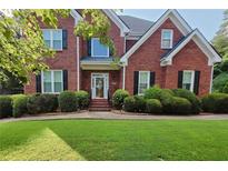 Charming two-story brick home with well-manicured lawn and lush, rounded shrubbery enhancing its curb appeal at 1205 Runnelwood Trail, Snellville, GA 30078