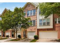 Charming brick townhome exterior featuring an attached garage and lush green trees at 1403 Ashford Creek Ne Cir, Atlanta, GA 30319