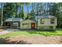Charming home featuring a covered carport, a red front door, and a lush front yard at 3195 Newcastle Way, Snellville, GA 30039