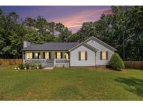 Charming single-story home featuring a cozy front porch, green lawn and landscaped garden at 136 Fairlane Dr, Covington, GA 30016