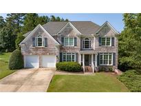Charming two-story brick home with a well-manicured lawn, two-car garage and attractive shutters at 4345 Mantle Ridge Dr, Cumming, GA 30041