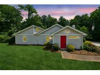 Charming single-story home with a well-maintained lawn and a vibrant red front door at 1480 Bettis Tribble Gap Rd, Cumming, GA 30040