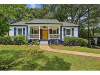 Charming home features a landscaped yard, inviting porch, and cheerful yellow front door at 1617 Columbia Cir, Decatur, GA 30032
