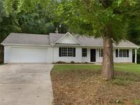 Charming single-story home featuring a well-manicured lawn, attached garage, and mature shade tree at 230 Myrtle Grove Ln, Covington, GA 30014