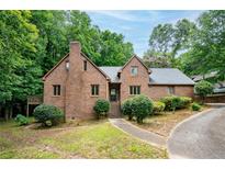 Charming brick home featuring mature trees, a walkway, and a covered entrance, offering a blend of classic and modern design at 9055 Green Valley Ct, Douglasville, GA 30134