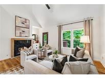 Bright living room features a fireplace, vaulted ceiling, and large windows with backyard views at 904 Ivy Green Se Ln, Marietta, GA 30067