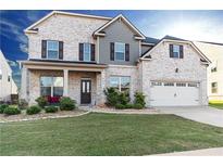 Charming two-story home with a brick facade, a well-manicured lawn and an attached two-car garage at 905 Eldridge Rd, Hampton, GA 30228