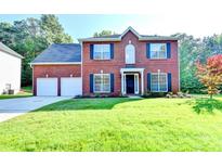 Inviting two-story brick home featuring a well-manicured lawn, two-car garage, and classic dark blue shutters at 2035 Lena Carter Rd, Buford, GA 30519