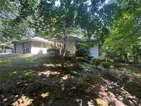 View of house exterior with lush foliage surrounding the home and a detached garage at 975 Willeo Rd, Roswell, GA 30075