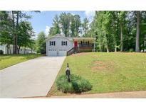 Charming two-story home with a well-manicured front lawn, driveway, and a red front door at 276 Indian Creek Dr, Powder Springs, GA 30127