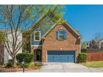 Charming two-story brick home featuring blue accents, a two-car garage, and a well-manicured front yard at 2075 Old Georgian Nw Ter, Atlanta, GA 30318