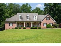 Charming brick home featuring a covered front porch, dormer windows, and manicured landscaping at 1642 Reflections Trl, Powder Springs, GA 30127