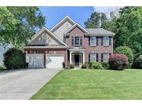 Charming two-story brick home with a well-manicured lawn, two-car garage, and beautifully landscaped front yard at 127 Bradshaw Park Dr, Woodstock, GA 30188