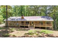 Charming ranch-style home with stone facade and a spacious wooden deck, nestled among lush trees at 257 Martin Ln, Canton, GA 30114