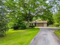 Charming single-story home with mature trees and a long driveway leading to an attached garage at 4380 Highway 138, Oxford, GA 30054