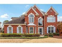 Charming two-story brick home with symmetrical design, arched windows, and well-manicured front yard at 7160 Fawn Lake Dr, Alpharetta, GA 30005