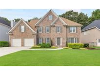 Charming brick home featuring a well-manicured lawn and a two-car garage at 8073 Ridge Vly, Woodstock, GA 30189