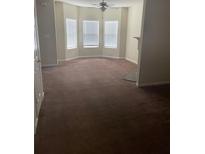 Spacious living room featuring three large windows, ceiling fan, and neutral carpeting at 8170 Oakley Cir, Union City, GA 30291