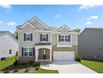 Charming two-story home with gray siding, stone accents, well-manicured lawn, and attached two-car garage at 865 Athena Bnd, Fairburn, GA 30213